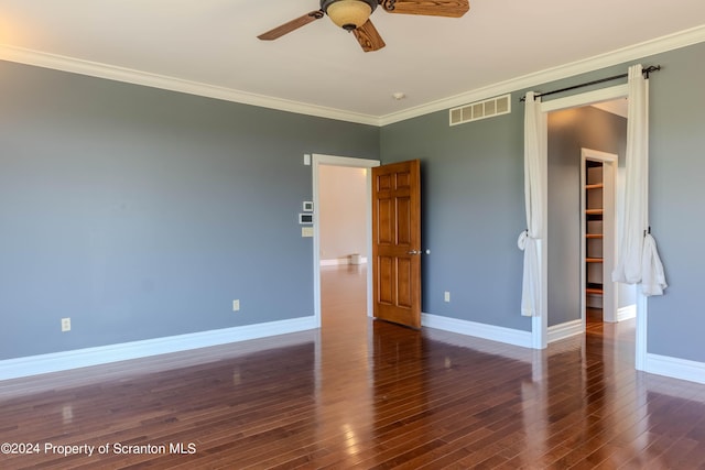 unfurnished bedroom with ceiling fan, dark hardwood / wood-style floors, crown molding, a walk in closet, and a closet