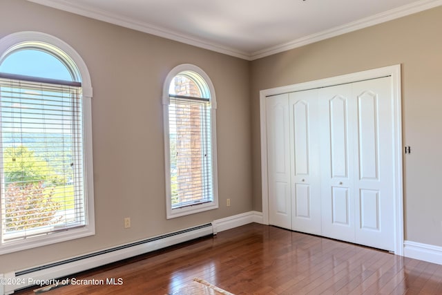 unfurnished bedroom featuring a closet, wood-type flooring, ornamental molding, and a baseboard radiator