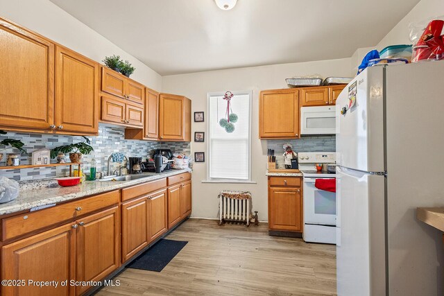 kitchen featuring white appliances, brown cabinetry, light wood-style floors, and light countertops