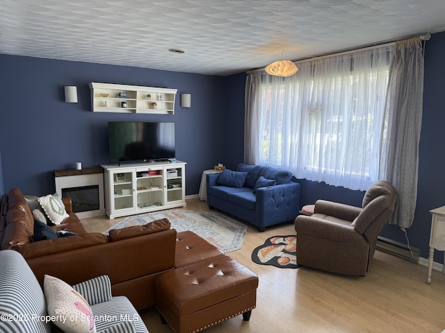 102 Bubernak Blvd, Old Forge, PA 18518 - living area featuring wood finished floors, a baseboard heating unit, baseboards, and a glass covered fireplace