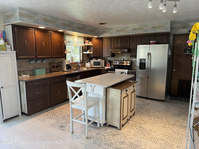 102 Bubernak Blvd, Old Forge, PA 18518 - kitchen featuring appliances with stainless steel finishes, dark brown cabinets, a sink, decorative backsplash, and a kitchen island