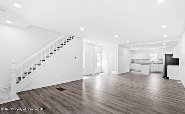 unfurnished living room featuring dark wood-type flooring and sink