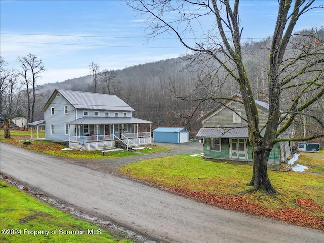 view of front facade featuring covered porch, a garage, a front lawn, and an outdoor structure