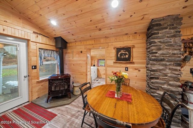 dining room with a healthy amount of sunlight, hardwood / wood-style flooring, a wood stove, and lofted ceiling