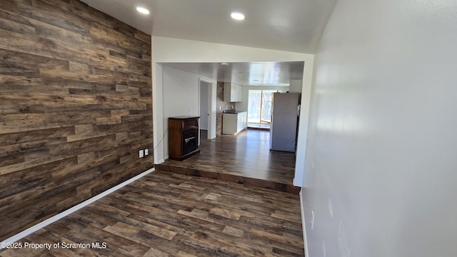 hallway with wooden walls, baseboards, lofted ceiling, recessed lighting, and dark wood-type flooring