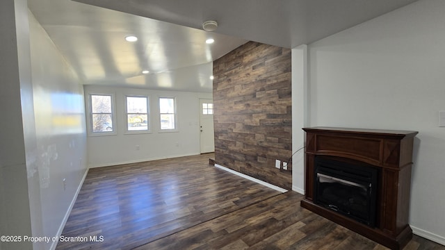 unfurnished living room with dark wood-style floors, a glass covered fireplace, recessed lighting, baseboards, and vaulted ceiling