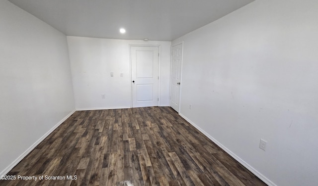 empty room featuring baseboards and dark wood-style flooring