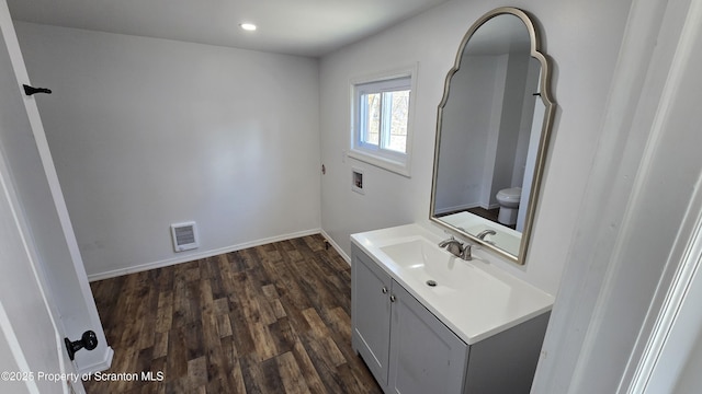 bathroom with vanity, wood finished floors, visible vents, baseboards, and toilet