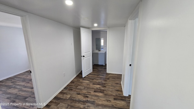 hallway featuring a sink, baseboards, dark wood finished floors, and recessed lighting