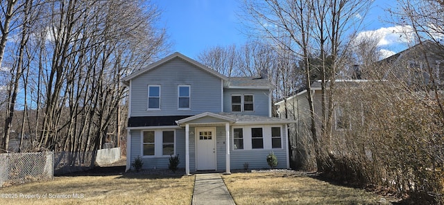 traditional home with roof with shingles, a front lawn, and fence