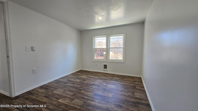 unfurnished room with baseboards and dark wood-style floors