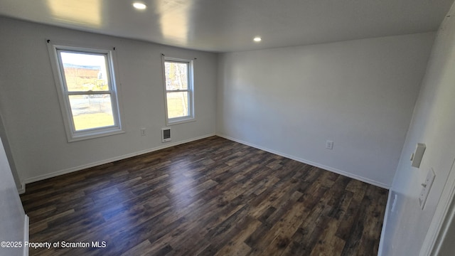 empty room featuring dark wood finished floors, visible vents, recessed lighting, and baseboards