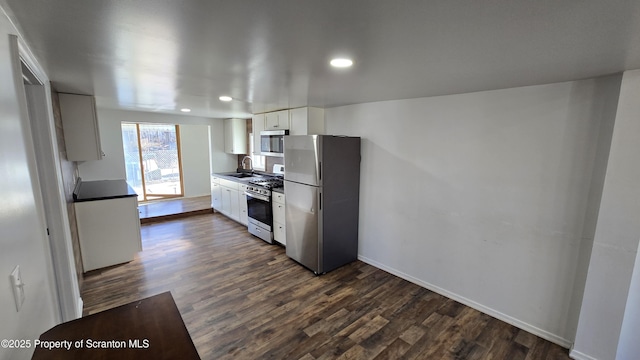 kitchen featuring baseboards, dark wood finished floors, stainless steel appliances, white cabinetry, and a sink