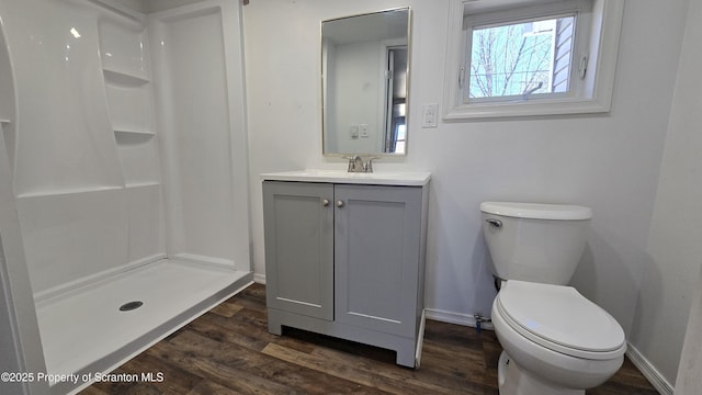 full bathroom featuring vanity, wood finished floors, baseboards, a stall shower, and toilet