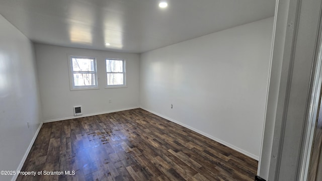 unfurnished room featuring visible vents, baseboards, and dark wood-type flooring