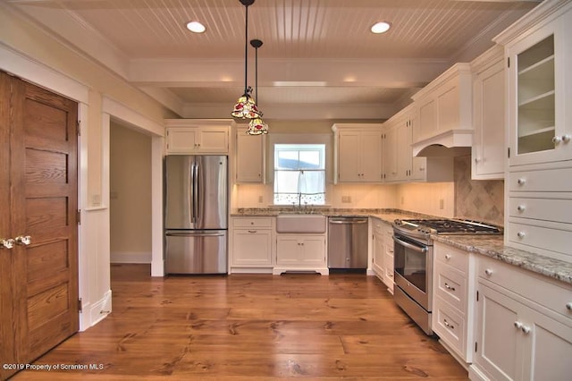 kitchen with white cabinetry, hanging light fixtures, light stone counters, appliances with stainless steel finishes, and light wood-type flooring