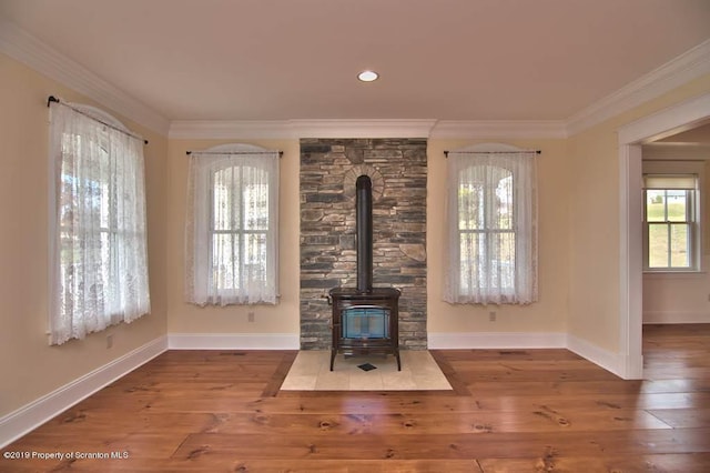 unfurnished living room featuring hardwood / wood-style floors, a wood stove, and ornamental molding