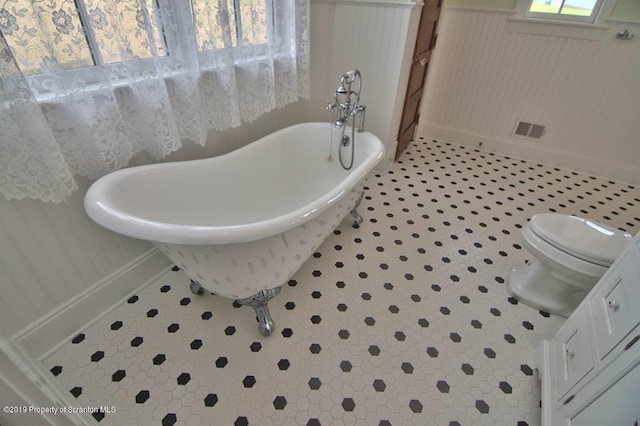 bathroom with a washtub, tile patterned flooring, and toilet