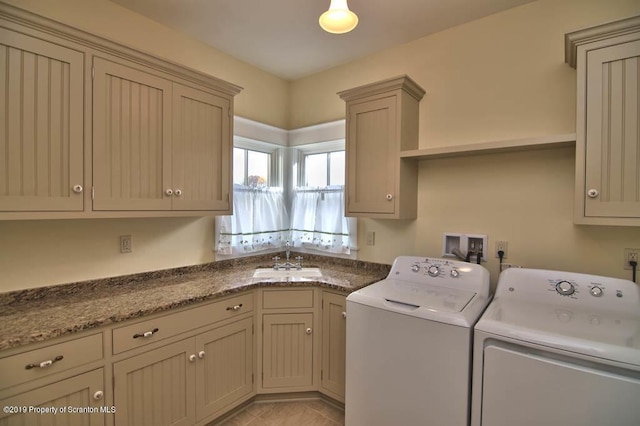 clothes washing area featuring washing machine and dryer, sink, light tile patterned floors, and cabinets