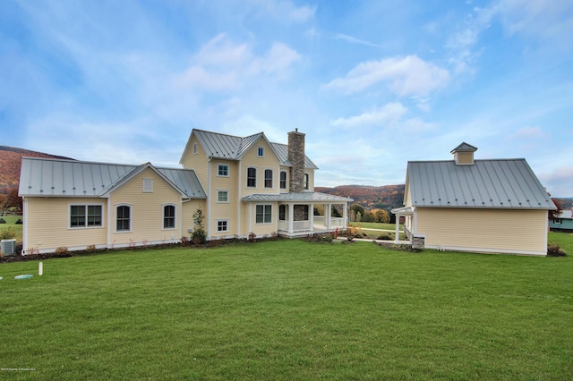 rear view of property featuring covered porch, a yard, and central AC