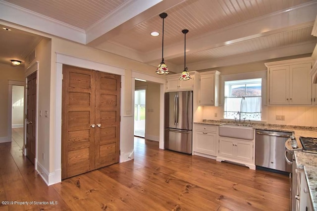 kitchen with light stone counters, stainless steel appliances, sink, decorative light fixtures, and white cabinets