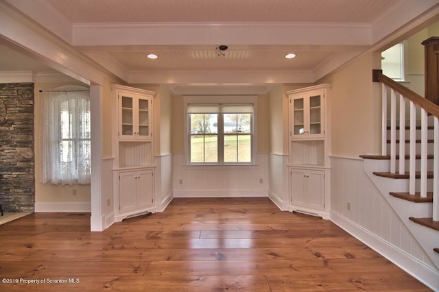 unfurnished dining area with hardwood / wood-style floors, beamed ceiling, and ornamental molding