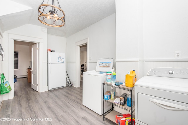 laundry area featuring a chandelier, washing machine and clothes dryer, and light wood-type flooring