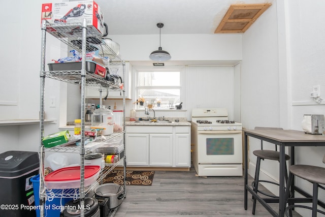 kitchen with dark wood-type flooring, sink, pendant lighting, white gas range oven, and white cabinets