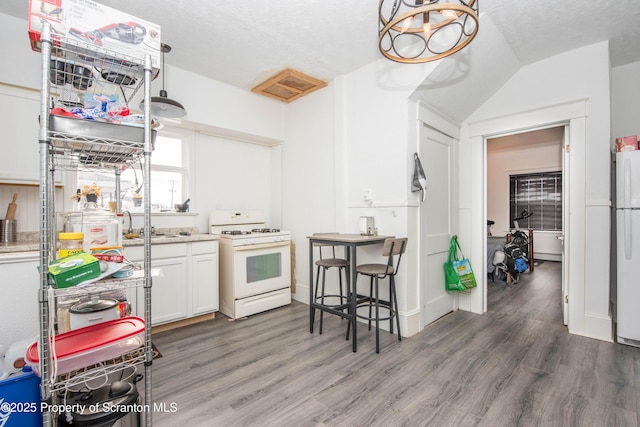 kitchen featuring white appliances, a textured ceiling, dark hardwood / wood-style floors, and white cabinets