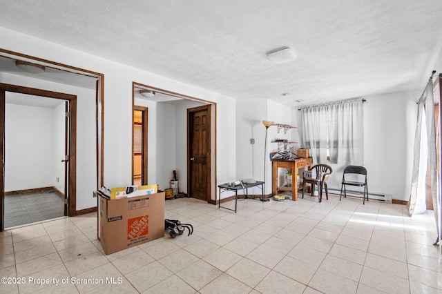 interior space featuring light tile patterned floors, baseboards, a textured ceiling, and a baseboard heating unit