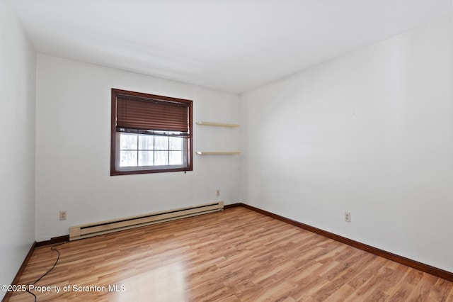 spare room featuring a baseboard radiator, baseboards, and wood finished floors