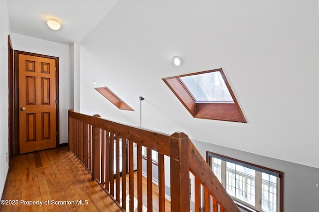 hallway featuring lofted ceiling with skylight and wood finished floors