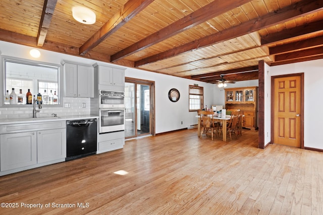 kitchen with black dishwasher, tasteful backsplash, white cabinets, light countertops, and double oven