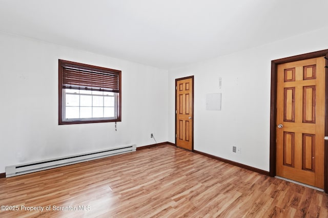 interior space featuring a baseboard heating unit, light wood-style flooring, and baseboards