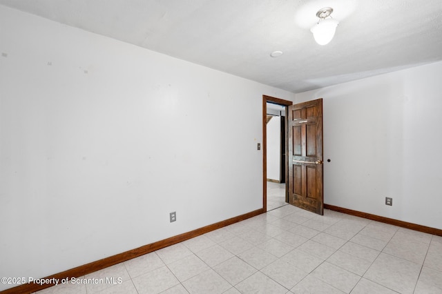 empty room with light tile patterned flooring and baseboards