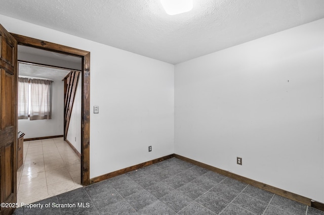 spare room with a textured ceiling and baseboards