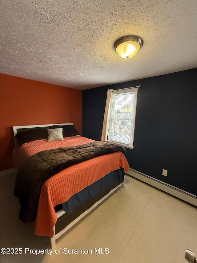 bedroom with a baseboard heating unit and a textured ceiling