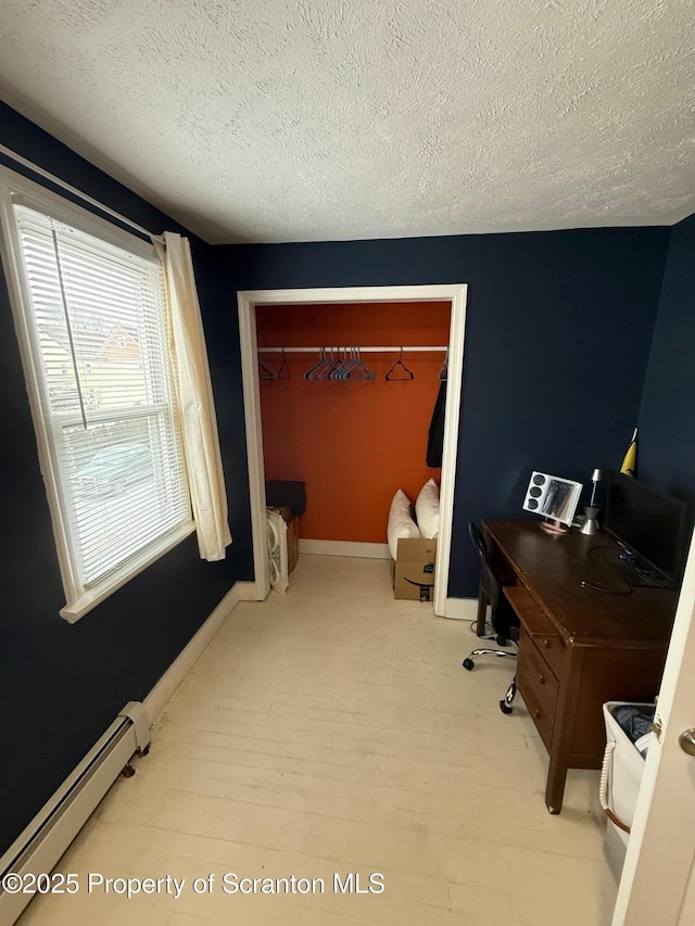 office space featuring a baseboard radiator, light hardwood / wood-style floors, and a textured ceiling