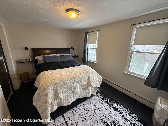 bedroom featuring a baseboard heating unit and a textured ceiling