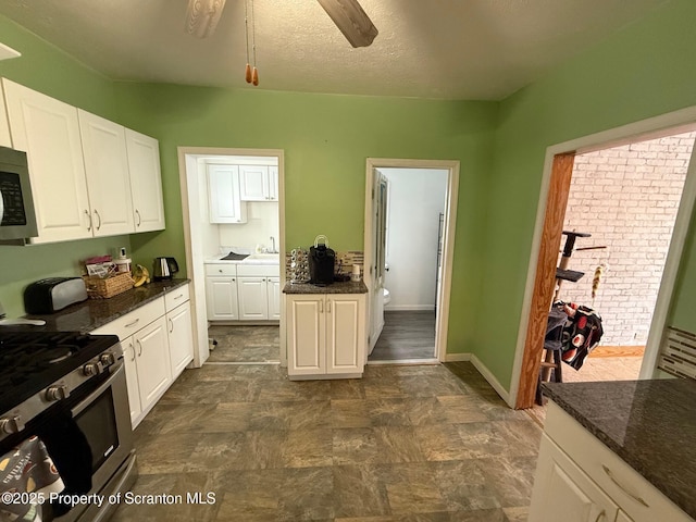 kitchen with white cabinetry, gas range, dark stone counters, and a textured ceiling