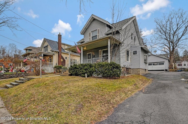 view of front of house featuring a porch, a garage, an outdoor structure, and a front yard