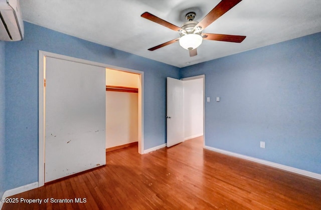 211 Hill St, Dupont, PA 18641 - unfurnished bedroom featuring wood finished floors, a wall unit AC, a closet, and a ceiling fan