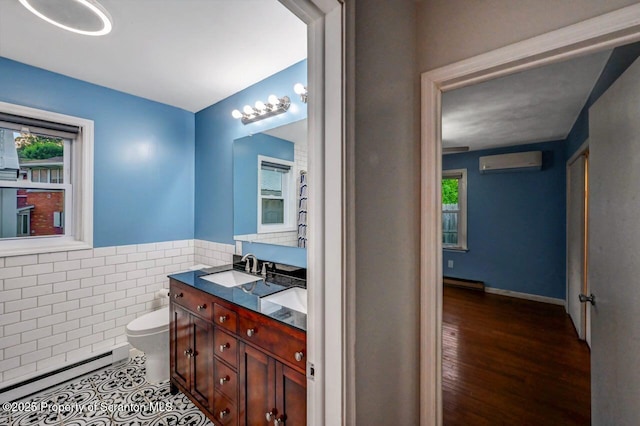 211 Hill St, Dupont, PA 18641 - bathroom with a wall mounted air conditioner, baseboard heating, tile walls, double vanity, and a wainscoted wall