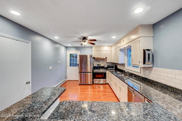 211 Hill St, Dupont, PA 18641 - kitchen featuring appliances with stainless steel finishes, a ceiling fan, light wood-type flooring, backsplash, and dark stone counters