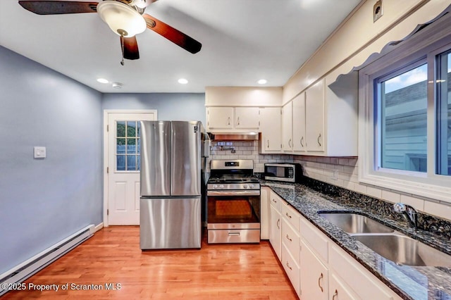 211 Hill St, Dupont, PA 18641 - kitchen with appliances with stainless steel finishes, a baseboard heating unit, under cabinet range hood, white cabinetry, and backsplash