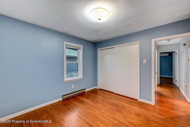 211 Hill St, Dupont, PA 18641 - unfurnished bedroom with a baseboard radiator, hardwood / wood-style flooring, and a closet