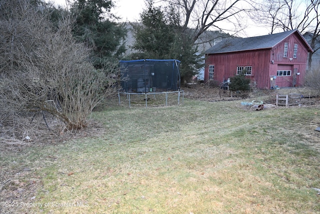 view of yard with a trampoline, an outdoor structure, and a barn