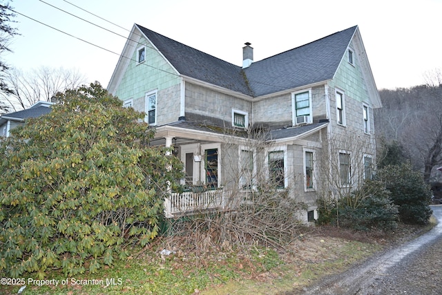 view of home's exterior featuring a porch, a shingled roof, and a chimney