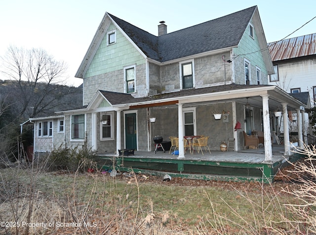 view of front of property featuring covered porch, a shingled roof, and a chimney