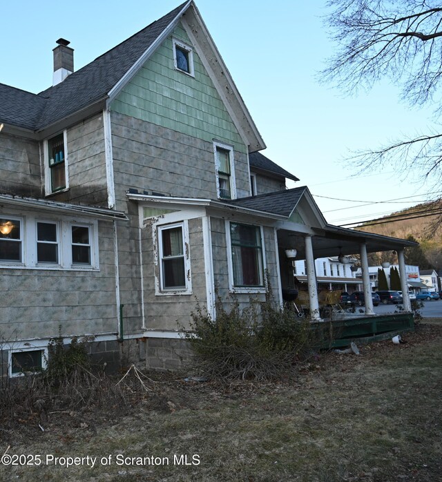 rear view of property with roof with shingles and a chimney